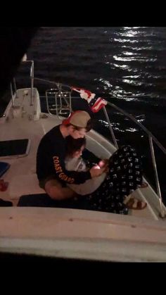 two people sitting on a boat in the water at night with an american flag flying above them