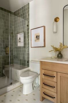 a white toilet sitting next to a shower in a bathroom under a framed picture on the wall