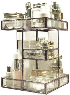 an assortment of cosmetics and perfume bottles on a metal shelving unit with mirror inserts