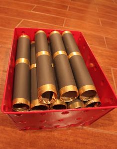 a red box filled with lots of gold and black tubes on top of a wooden floor