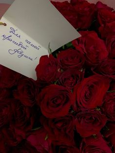 a bouquet of red roses with a note attached to it