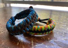 two adjustable fishtail bracelets sitting side by side made with colorful paracord and center-stitched with microcord. Paracord Fishtail, Paracord Zipper Pull, Fishtail Bracelet, Color Catalog, Paracord Projects, A Compass, Walking Stick, Walking Sticks, Survival Kit