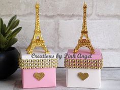 two small boxes with gold and pink designs on them, one is shaped like the eiffel tower