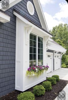 a white and black house with some flowers in the window boxes on the side of it