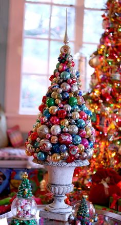 a christmas tree made out of ornaments in front of a decorated christmas tree with lights