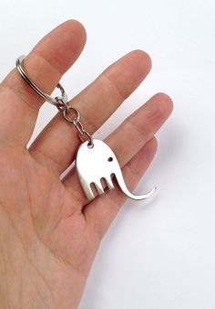 a hand holding a metal elephant shaped keychain