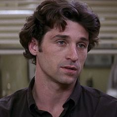 a close up of a person wearing a black shirt and looking at the camera with a serious look on his face