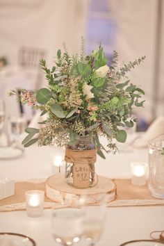 a vase filled with flowers sitting on top of a table next to glasses and candles