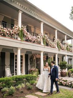 a bride and groom standing in front of a building with flowers on the balconies