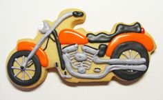 a cookie shaped like a motorcycle with orange and black paint on the front, sitting on a white surface