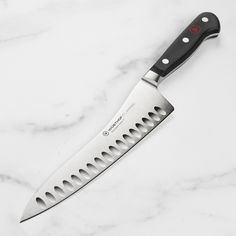 a large knife sitting on top of a white marble counter next to a black handle