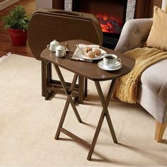 a table with two cups of coffee on it in front of a couch and fireplace