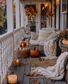 a porch decorated for fall with pumpkins, candles and wicker furniture on the front porch