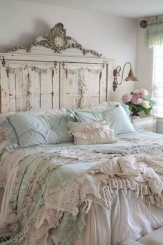 a white bed with lots of pillows and blankets on it's headboard in a bedroom