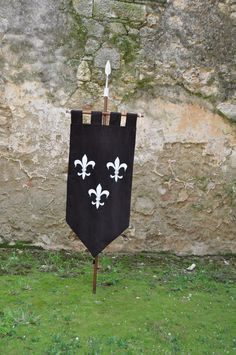 a black banner with white fleur de lis on it in front of a stone wall