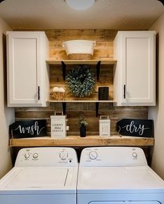 a washer and dryer in a room with wooden shelves on the wall above them