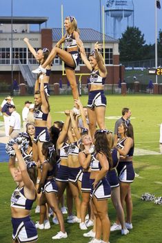 a group of cheerleaders standing on top of each other at a football game