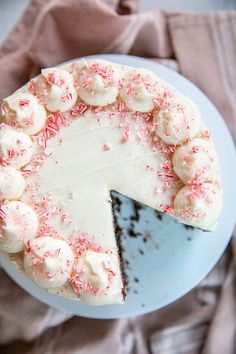 a cake with white frosting and pink sprinkles on top is sitting on a plate