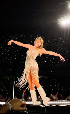 a woman is performing on stage with her arms outstretched and legs spread out in the air