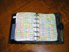 an open bible on top of a wooden table with a pen in the book holder