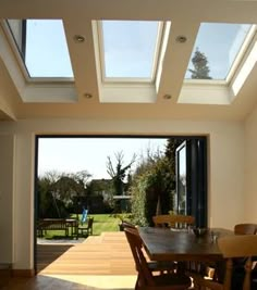 a dining room table and chairs with skylights on the ceiling above it in front of an open patio door