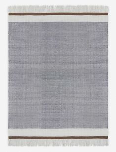 a gray rug with fringes on the bottom and brown trim around the edges, against a white background