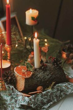 a table topped with candles and fruit on top of a cloth covered table next to other decorations