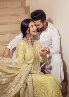 a man and woman sitting next to each other on the stairs smiling at each other