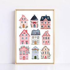 a pink and blue house print hanging on a wall next to a white wall with a gold frame