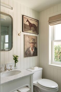 a bathroom with a toilet, sink and pictures on the wall above it's mirror