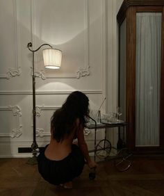 a woman sitting on the floor in front of a lamp