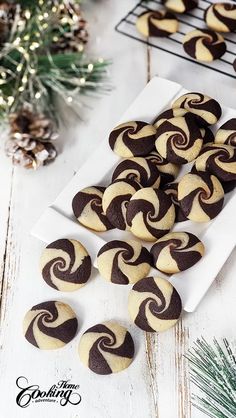 chocolate swirl cookies on a white plate next to pine cones and christmas decorations in the background