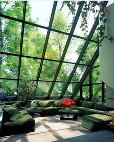 a living room filled with lots of furniture under a large glass ceiling covered in trees