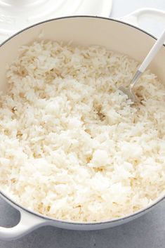 rice is being cooked in a pot on the stove with a ladle and spoon