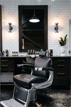 a black and white barber chair in front of a mirror with lights on the wall