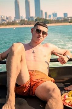 a man sitting on the back of a boat holding a plate of fruit in his hand