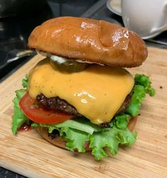 a cheeseburger with lettuce and tomatoes on a wooden cutting board