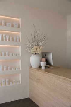 a vase filled with flowers sitting on top of a wooden counter next to a computer