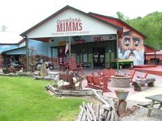 an old fashioned fire station with wooden chairs and logs in the foreground, along with a large mural on the building