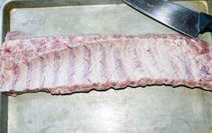 raw meat is being prepared on a metal tray with a large knife next to it