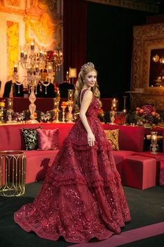 a woman in a red dress is standing on a stage with candles and decorations behind her