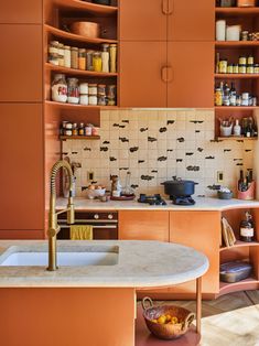 a kitchen with orange cabinets and an island in front of the sink, filled with spices