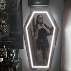 a woman taking a selfie with her cell phone in front of a lighted mirror