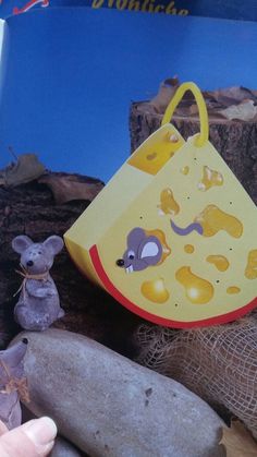 a hand holding a yellow bag next to rocks and a mouse