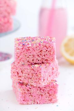 three pieces of pink cake sitting on top of a white table with sprinkles