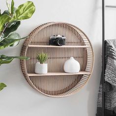 a round shelf with two plants on it next to a wall mounted camera and potted plant