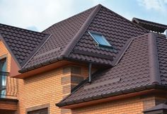 a brown brick house with two dormers on the roof and one window in the corner