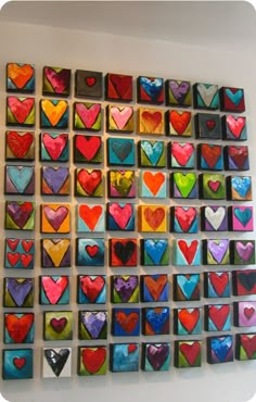 many different colored hearts are arranged on the wall