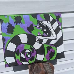 a painting of a dinosaur with purple and green stripes on it's face, in front of a white building