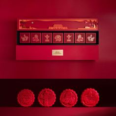 three red wax stamps sitting on top of a shelf in front of a red wall